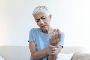 Elderly woman suffering from pain in hand, arthritis old person and senior woman female suffering from pain at home